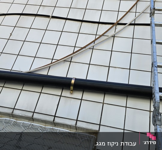 צינור שחור עם תושבת על קיר מרוצף